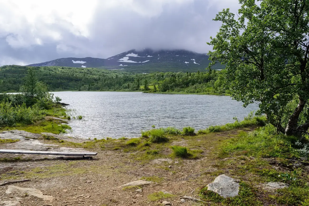 Lillådammen på Åreskutans sluttning i juli, med fjälltoppar och snöfläckar i bakgrunden.